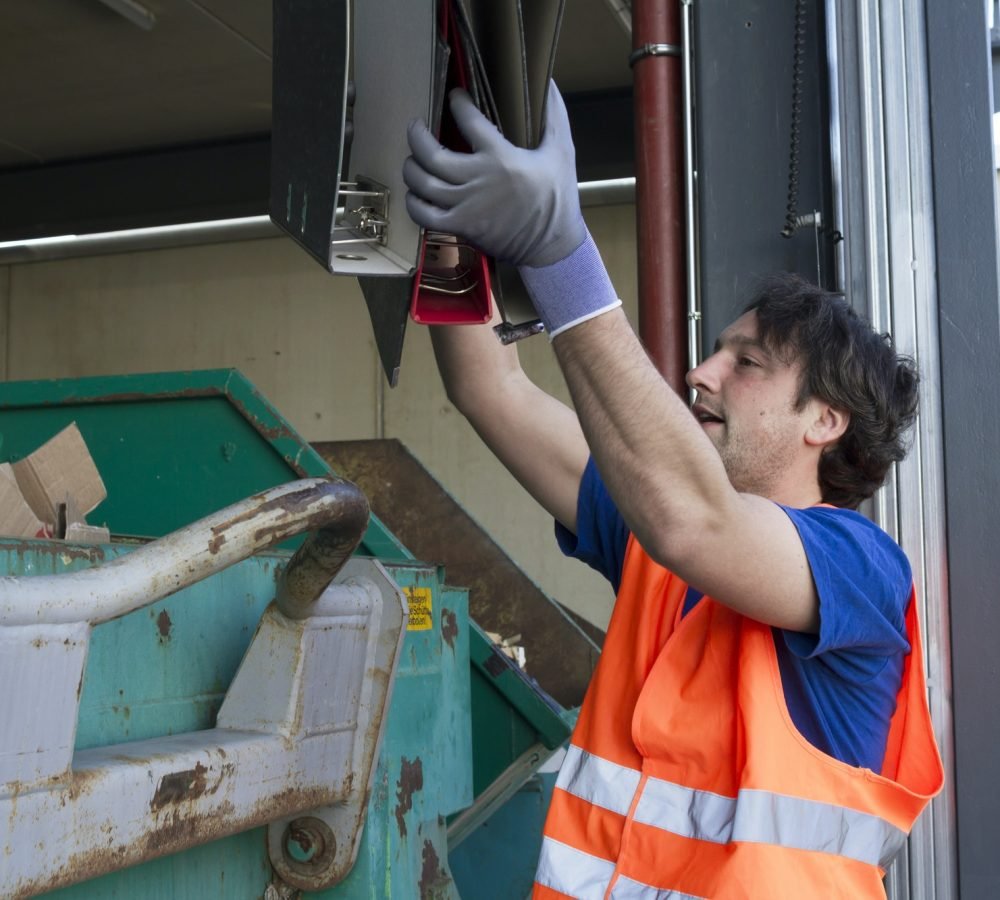 worker-at-a-waste-container-throwing-away-folders.jpg